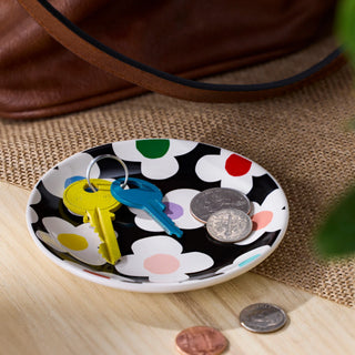 Demdaco Floral Toss black and white trinket dish holding colorful keys and coins on wooden surface