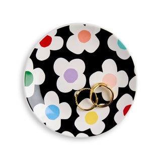 Round black trinket dish with white daisy flowers and colorful centers, holding two gold rings
