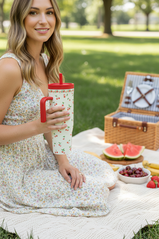 Woman holding 40oz Rifle Paper Cherries Cruiser at outdoor picnic