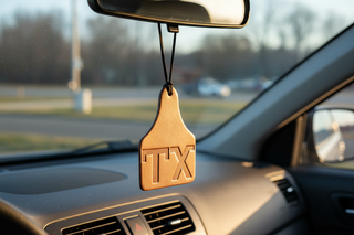 Cow Tag Air Flair hanging from a car rearview mirror