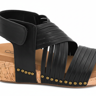 Close-up detail of black wedge sandal straps and gold studs