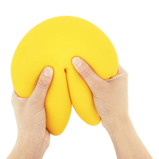 Two hands squeezing a large yellow squishy fortune cookie stress toy against white background