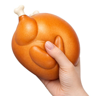 Hand squeezing a large golden-brown squishy toy shaped like a roasted turkey with bone
