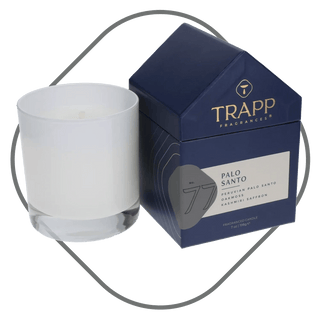 Trapp Palo Santo candle in white frosted glass beside navy house-shaped gift box with gold foil logo