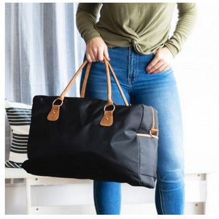 Black nylon travel bag with tan vegan leather accents, adjustable strap and side zip pocket