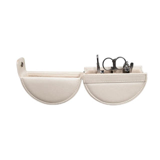 Flat lay cream semi-circular travel manicure set showing organized stainless steel tools