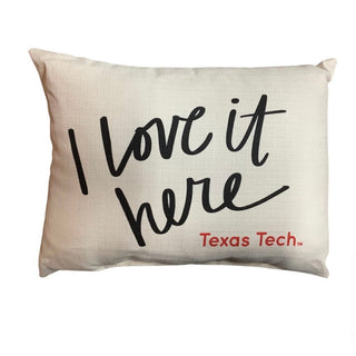 Off-white linen-texture rectangular pillow with black cursive 'I love it here' and red Texas Tech logo