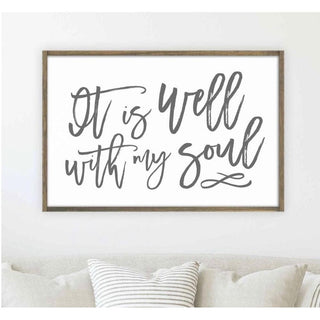 It Is Well 24x36 Wood Sign with rustic dark brown reclaimed wood frame and gray brush-lettering on white wall