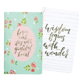 Notebook with floral design and motivational quote on cover, open to lined pages.