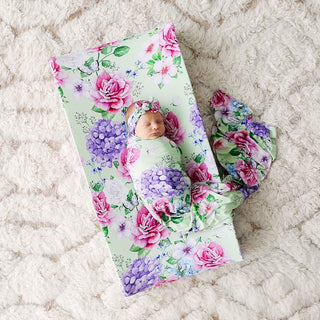 Newborn baby on Posh Peanut Georgina floral changing pad cover with matching swaddle on nursery rug