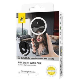 Illuminated black ring light clipped to smartphone displaying selfie mode in living room