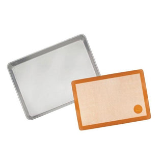 Orange-brown silicone baking mat beside aluminum baking sheet showing size comparison and oven compatibility