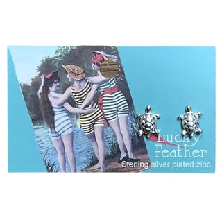 Sterling silver plated zinc turtle stud earrings with textured shell ridges on turquoise Lucky Feather card