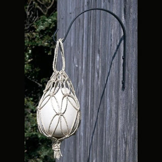 White Skeeter Screen Patio Egg hanging in macramé netting on wooden fence for outdoor mosquito control