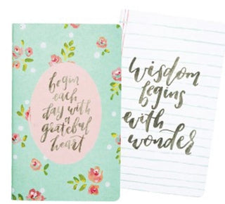 Notebook with floral design and motivational quote on cover, open to lined pages.